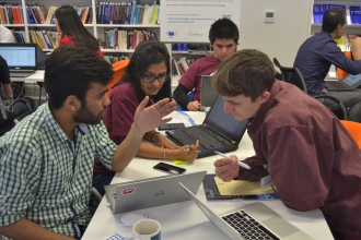 Three participants sat around a laptop at ECMWF's #OpenDataHack exploring creative uses of open data.