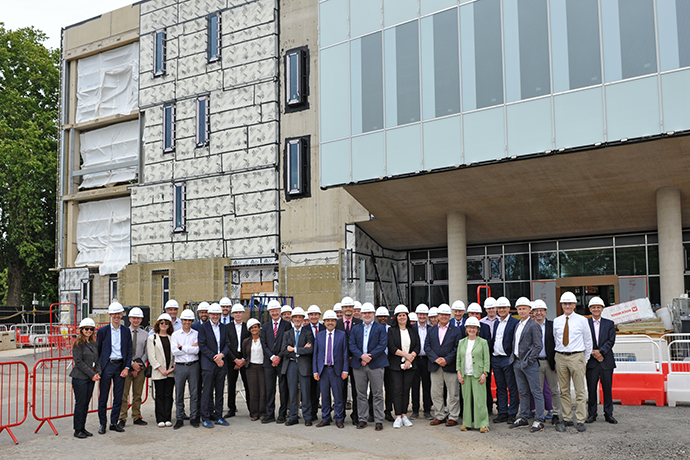 Large group of people in white hard hats lined up in front of the new and under construction Reading ECMWF HQ building