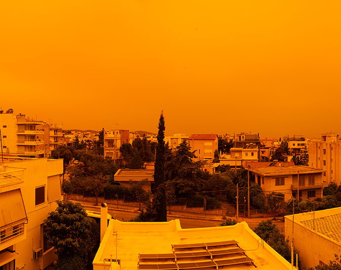 Urban neighbourhood beneath an orange, hazy sky caused by air pollution.