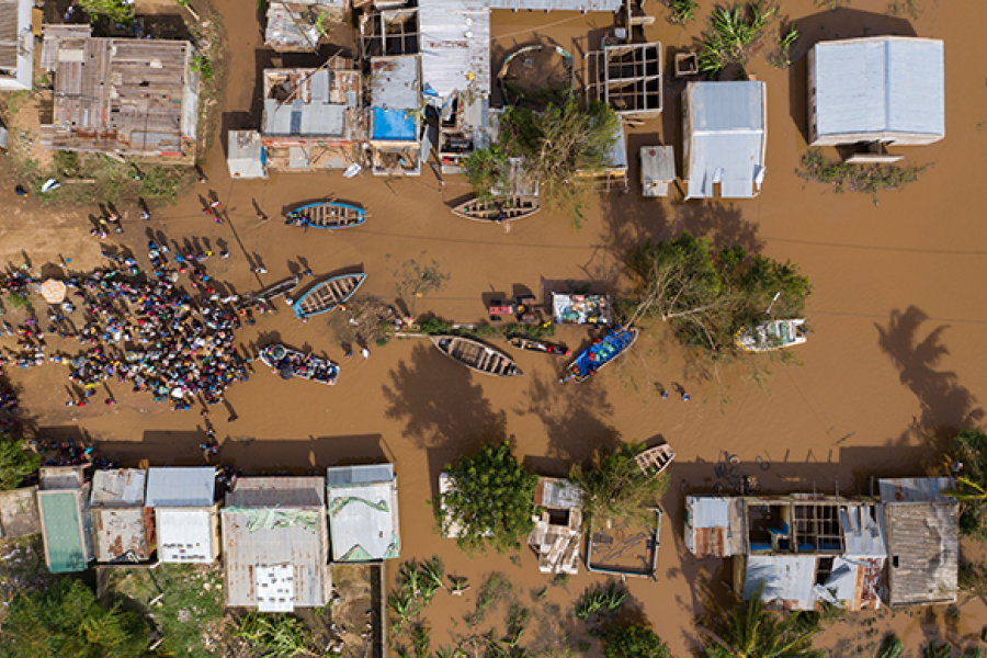 Overhead photo from a drone showing flooding, buildings and people gathering in a group with boats