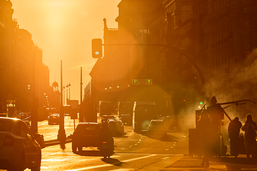 Urban street scene during an intense heatwave, with bright sunlight, traffic, and heat haze rising from the road.