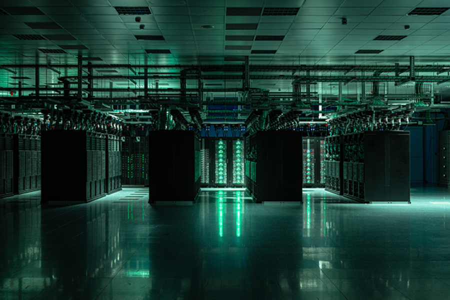 Rows of high-performance computing servers in ECMWF's data centre in Bologna, Italy, with illuminated server racks, overhead cabling and a reflective floor, supporting large-scale weather and climate modelling.