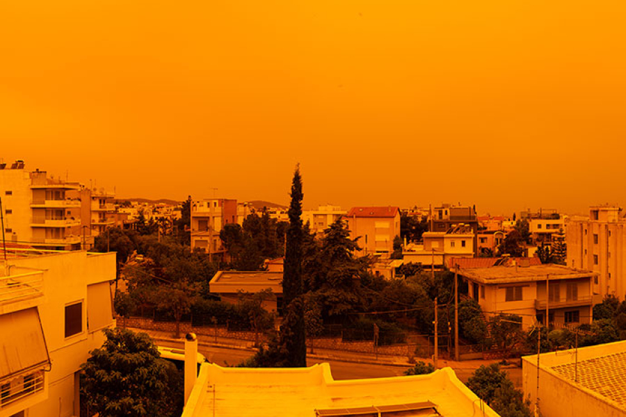 Urban neighbourhood beneath an orange, hazy sky caused by air pollution.