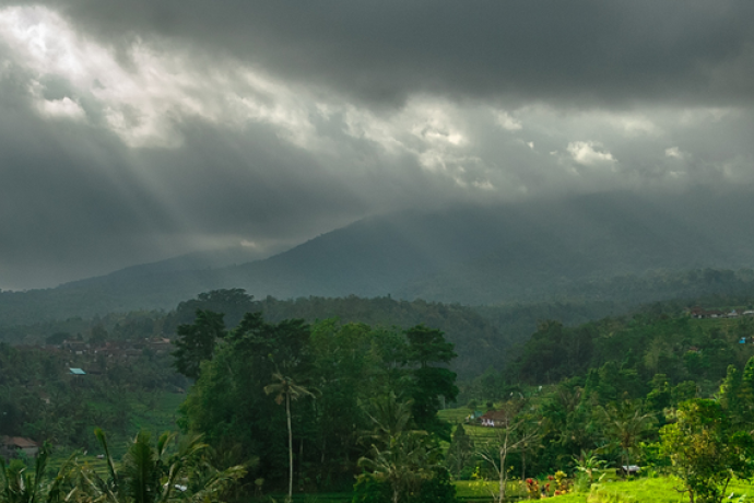 A green landscape in Indonesia with a dark grey sky above