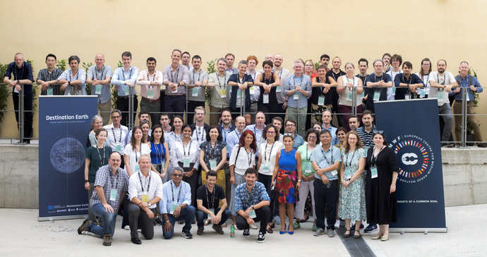 3rd ECMWF Destination Earth Annual Meeting in Bologna Large group photo with two small blue banner posters either side of the group. The posters are blue with the left one with the Destnation Earth logo and the right one with the 50th anniversary logo on.