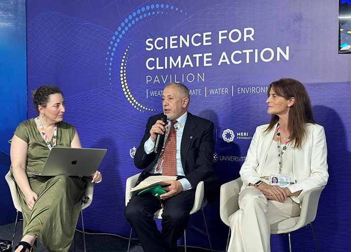Florence Rabier sat with two people in front of a blue background that has white words reading "science for climate action pavilion" written on.