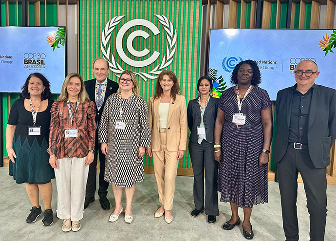 A group of eight people stood for a photo in front of a green background with a white UNFCCC logo on
