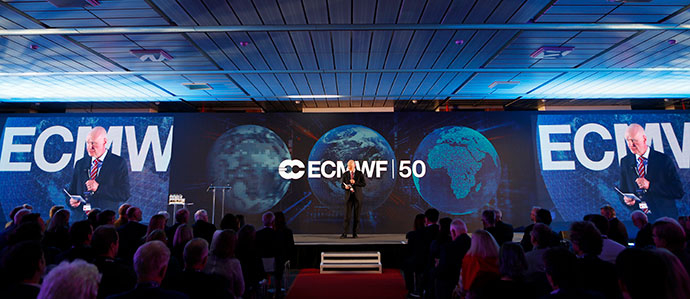Roar Skålin on a stage in front of screens that show the ECMWF 50 logo laid on top of three globes