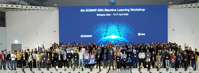 Very large group of people posing for a photo. Behind them is a large blue screen with the white words "5th ECMWF ESA Machine Learning Workshop"