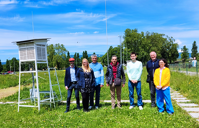 Seven people stood in a row outside on grass next to meteorological monitoring equipment