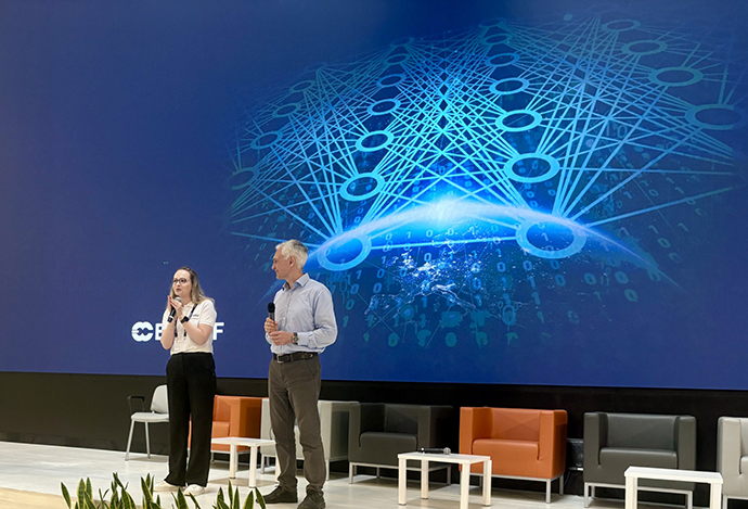 Rochelle Schneider (ESA) and Massimo Bonavita (ECMWF), stood in front of a large blue screen holding microphones
